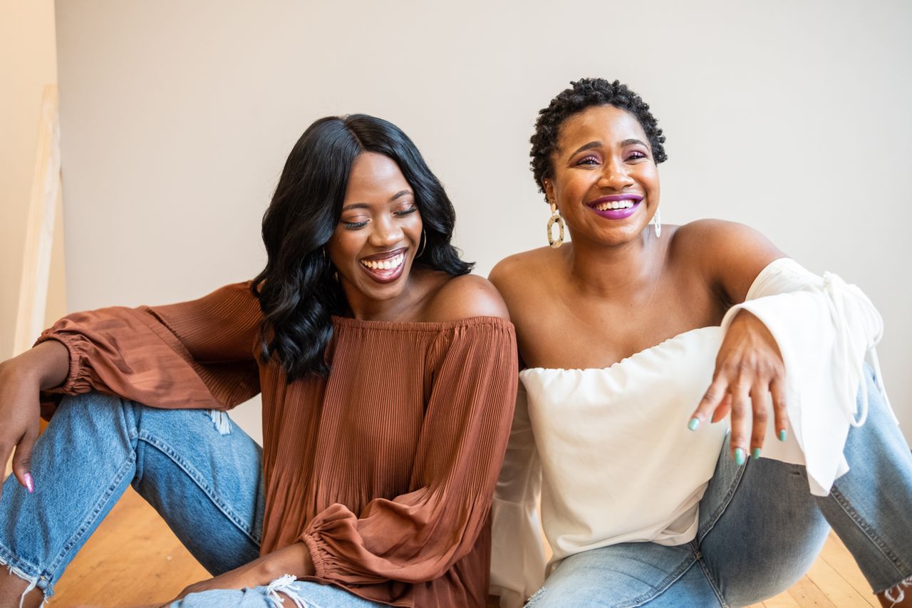Two African American women laughing and enjoying each other's company indoors.